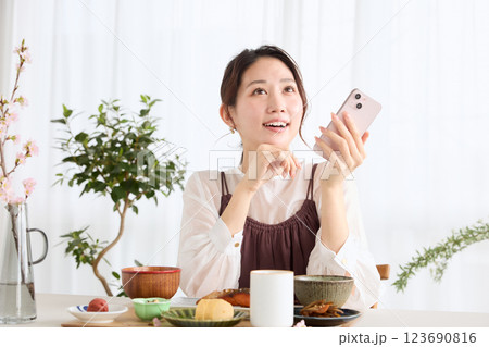 朝食にスマートフォンを見る女性 朝食にスマートフォンを見る女性 123690816