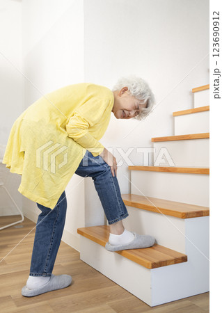 膝をおさえながら階段を登るシニア女性 123690912
