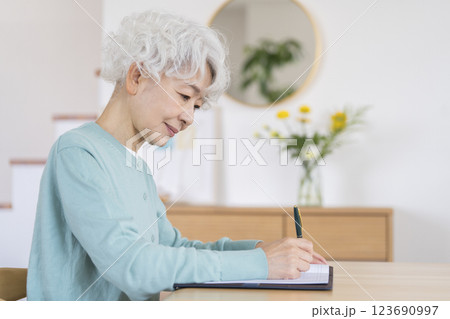 ペンを持って書き物をするシニア女性の横顔 123690997