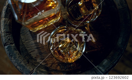 Detail of pouring ice cube into whiskey. Freeze motion drink preparation. Detail of pouring ice cube into whiskey. Freeze motion drink preparation. 123692602
