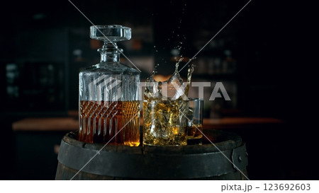 Detail of pouring ice cube into whiskey. Freeze motion drink preparation. Detail of pouring ice cube into whiskey. Freeze motion drink preparation. 123692603
