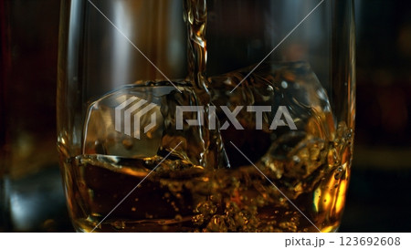 Detail of pouring whiskey into glass. Freeze motion drink preparation. Detail of pouring whiskey into glass. Freeze motion drink preparation. 123692608