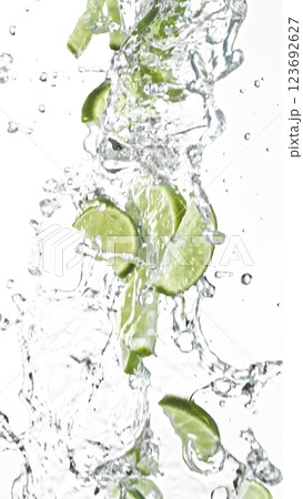 Fresh limes slices falling in water splashes, isolated on white background. 123692627