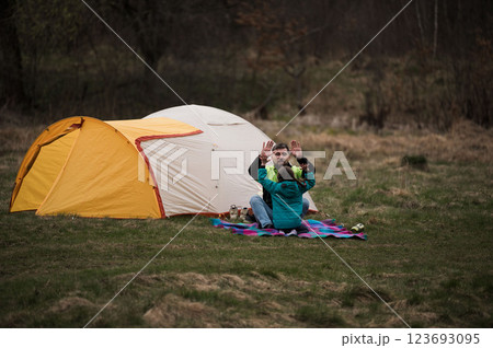 Family bonding time in nature by a cozy tent during a crisp evening, enjoying laughter and warmth under the vast sky Family bonding time in nature by a cozy tent during a crisp evening, enjoying laughter and warmth under the vast sky 123693095