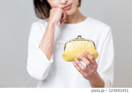 黄色のがま口財布を持って悩むミドル女性 123693451
