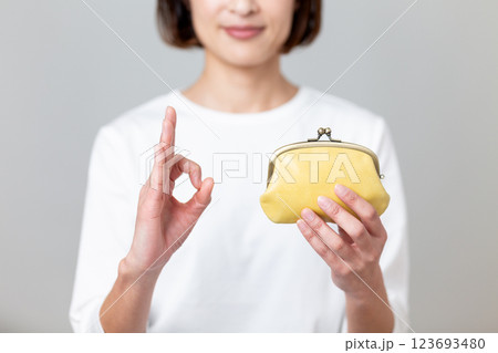 黄色のがま口財布を持って丸サインをするミドル女性 123693480