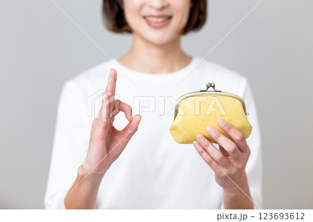 黄色のがま口財布を持って笑顔で丸サインをするミドル女性 123693612