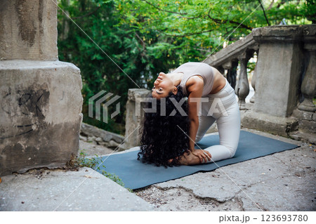 Brunette woman doing gymnastics yoga asana outdoors Brunette woman doing gymnastics yoga asana outdoors 123693780