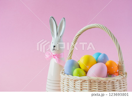 Basket with colorful Easter eggs and Bunny on a pink background, copy space 123693801