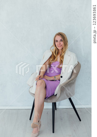 Beautiful blonde woman sitting on a chair in purple summer dress 123693861