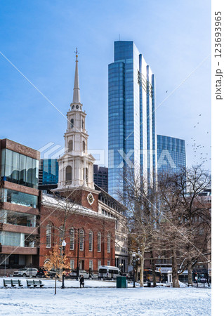 View of Park Street Church and surrounded buildings in Boston during winter with snow on the Boston Common ground and flock of birds flying against clear blue sky View of Park Street Church and surrounded buildings in Boston during winter with snow on the Boston Common ground and flock of birds flying against clear blue sky 123693965