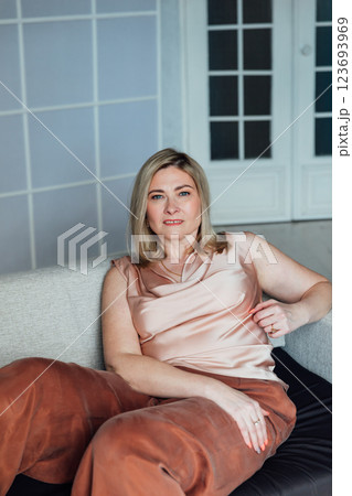 Woman in home clothes sitting on sofa in white room interior 123693969