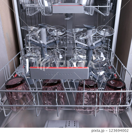 Wine glasses in dishwasher. Clean and tidy. Organizing dishes on holder, loading dirty items. Wine glasses in dishwasher. Clean and tidy. Organizing dishes on holder, loading dirty items. 123694002