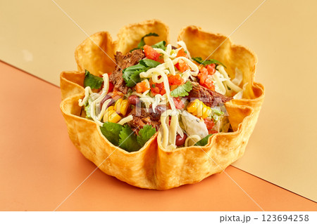 Taco salad in tortilla bowl with beef, cheese, corn and lettuce Taco salad in tortilla bowl with beef, cheese, corn and lettuce 123694258