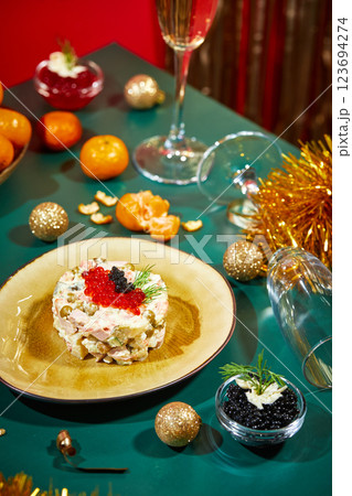 New Year's or Christmas table setting for party in Russian style with champagne in glass, tangerines and portioned Olivier salad on plate decorated with red and black caviar New Year's or Christmas table setting for party in Russian style with champagne in glass, tangerines and portioned Olivier salad on plate decorated with red and black caviar 123694274