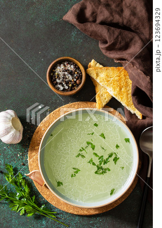 Healthy lunch. Hot rich meat broth (bouillon) with herbs and garlic croutons on a dark slate countertop. Top view flat lay background. Copy space. Healthy lunch. Hot rich meat broth (bouillon) with herbs and garlic croutons on a dark slate countertop. Top view flat lay background. Copy space. 123694329