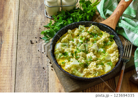 Diet breakfast or healthy lunch. Egg omelet with cauliflower in a cast-iron pan on rustic wooden table. Copy space. 123694335