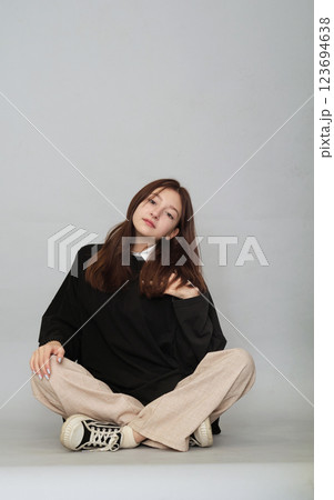 A 13-year-old sits pensively, her plain black hoodie serving as a mockup for your unique logo or design. A 13-year-old sits pensively, her plain black hoodie serving as a mockup for your unique logo or design. 123694638