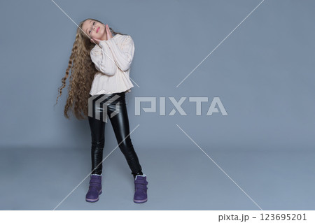 A girl with long, voluminous curly hair enjoys a carefree moment, showcasing her healthy and shiny locks. The scene emphasizes the importance of children's hair care, highlighting the benefits of 123695201