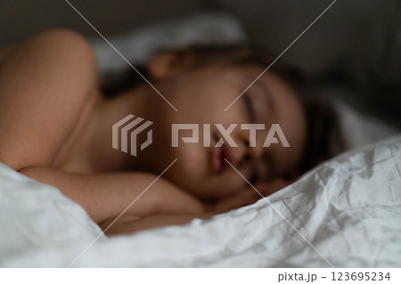 Young boy rests soundly in bed, wrapped in soft blankets, creating a calm and cozy atmosphere. 123695234