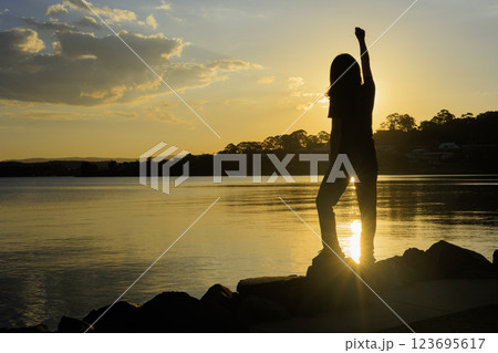 夕日に向かって手を広げる少女 123695617
