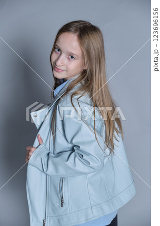 Girl glancing back, her light blue jacket adding a touch of style. Perfect for themes of curiosity and youthful fashion. 123696156
