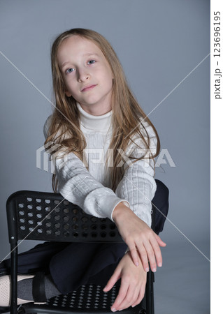 Young girl s tranquil expression as she lounges, the texture of her sweater suggesting softness and warmth. Ideal for winter wear. Young girl s tranquil expression as she lounges, the texture of her sweater suggesting softness and warmth. Ideal for winter wear. 123696195