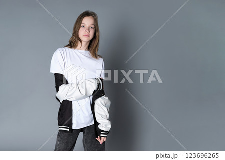 A girl in a casual varsity jacket looks straight ahead, projecting confidence and self-assurance. Her stance symbolizes the emerging identity and independence of today s young generation. 123696265