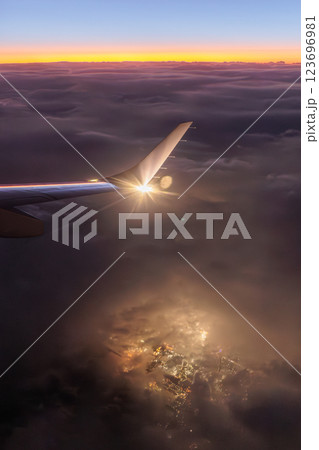 飛行機の窓の外（夕焼けと夜景と雲） 123696981
