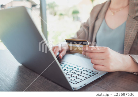 Woman holding credit card while using laptop and shopping outdoor at coffee shop, Woman holding credit card while using laptop and shopping outdoor at coffee shop, 123697536