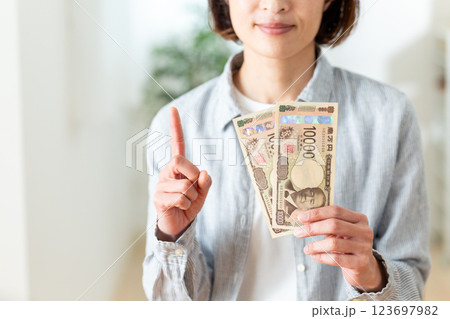 一万円札を二枚持って人差し指を立てるミドル女性 123697982