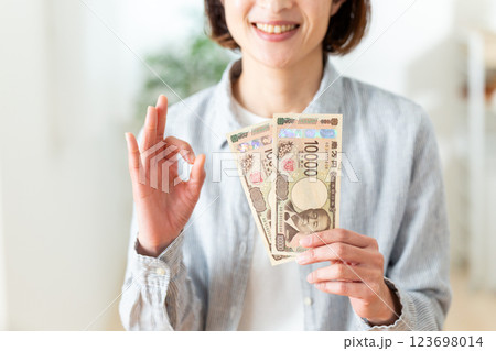 一万円札を二枚持って笑顔で丸サインをするミドル女性 一万円札を二枚持って笑顔で丸サインをするミドル女性 123698014