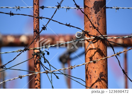 錆びついた鉄柵に絡まる有刺鉄線 123698472