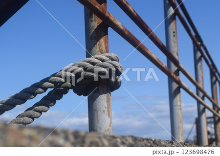 錆びた鉄柵の支柱に結ばれた古いロープ 123698476