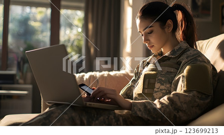 female soldier using laptop and phone at home 123699213