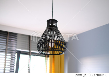 A black lamp with a yellow cord hanging from it. 123700040