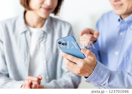 家でスマホを見ながら楽しそうに会話をするミドル夫婦 家でスマホを見ながら楽しそうに会話をするミドル夫婦 123701098