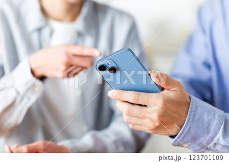 家でスマホを見ながら楽しそうに会話をするミドル夫婦 家でスマホを見ながら楽しそうに会話をするミドル夫婦 123701109