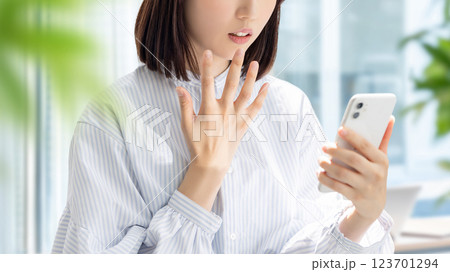 スマートフォンの画面を見て驚く女性・ビジネスウーマン スマートフォンの画面を見て驚く女性・ビジネスウーマン 123701294