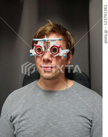 Male patient sits comfortably for precise eye examination, sight evaluation utilizing phoropter, sight calibration optimal prescription 123701361