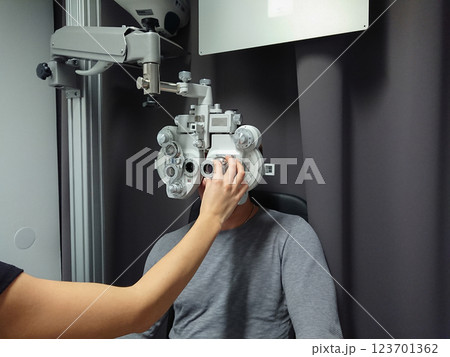 Man in professional clinic wearing phoropter for eye assessment, vision test, and precise lens measurements. Vision improvement concept 123701362