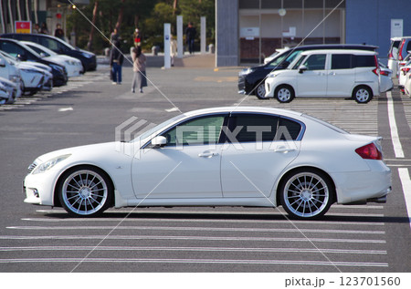 観光地の駐車場に停めたDセグメントの国産4ドアセダンのサイドビュー（21インチホイール装着イメージ） 123701560