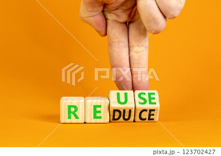 Reuse or reduce symbol. Concept words Reuse Reduce on wooden block. Beautiful orange table orange background. Businessman hand. Business reuse or reduce concept. Copy space. 123702427