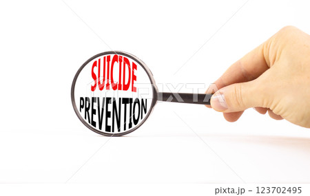 Suicide prevention symbol. Concept words Suicide prevention on beautiful magnifying glass. Beautiful white table background. Psychologist hand. Psychological suicide prevention concept. Copy space. 123702495