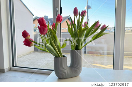 Elegant tulip bouquet in a modern vase near a window, spring decor 123702917