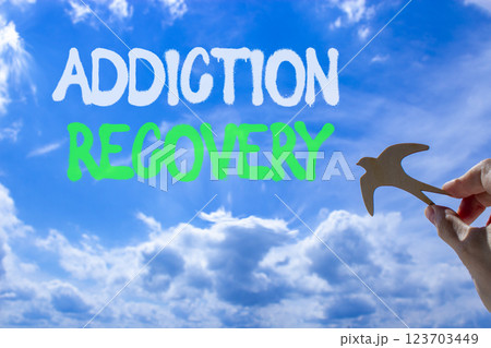 Addiction recovery symbol. Concept words Addiction recovery on beautiful blue sky. Psychologist hand, wooden bird. Beautiful blue sky cloud background. Psychology addiction recovery concept Copy space 123703449
