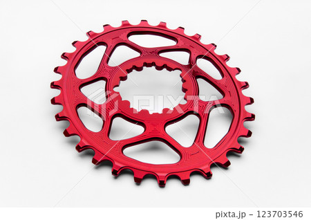 Red oval bicycle chainring against white isolated background, lies flat on the surface. Professional bicycle part. 123703546