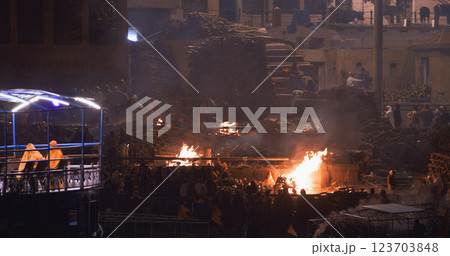 Varanasi, Uttar Pradesh, India. Cremation in process on Manikarnika Ghat. Cinematic Camera movement moving along riverbank embankment. View from riverside. night lights. Fire, smoke - Funeral rites of Varanasi, Uttar Pradesh, India. Cremation in process on Manikarnika Ghat. Cinematic Camera movement moving along riverbank embankment. View from riverside. night lights. Fire, smoke - Funeral rites of 123703848