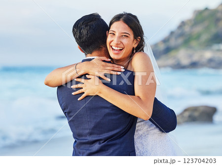 Portrait, hug and bride with groom by beach for commitment, care or bonding together. Sea, travel and couple with embracing moment at romantic, tropical and destination marriage ceremony by ocean. 123704203