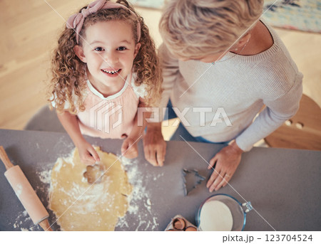 Food, family and portrait of girl baking with grandmother in kitchen, happy, relax and prepare cookies together. Learning, growth and child development by kid and granny have fun with shape and flour 123704524